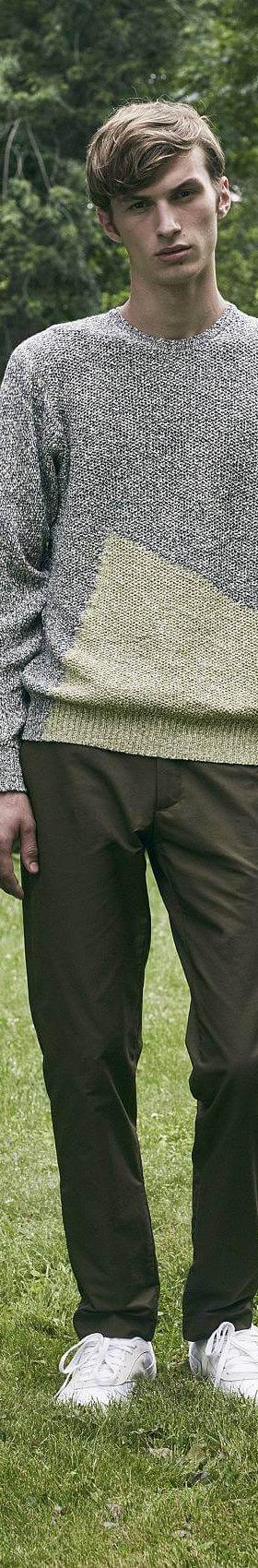 A man wearing a grey colour-blocked DDUGOFF sweater with brown trousers
