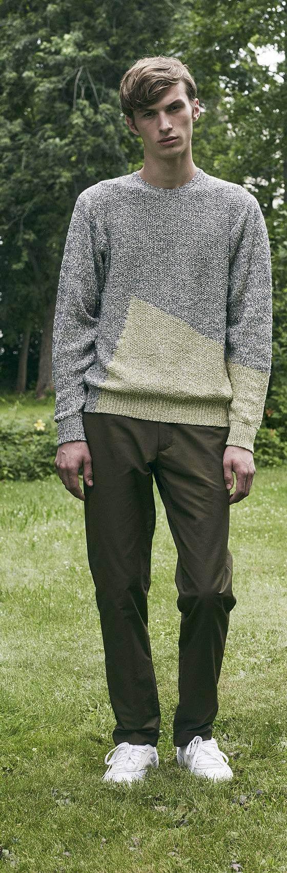 A man wearing a grey colour-blocked DDUGOFF sweater with brown trousers