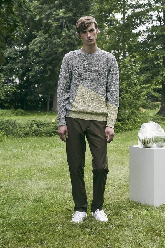 A man wearing a grey colour-blocked DDUGOFF sweater with brown trousers