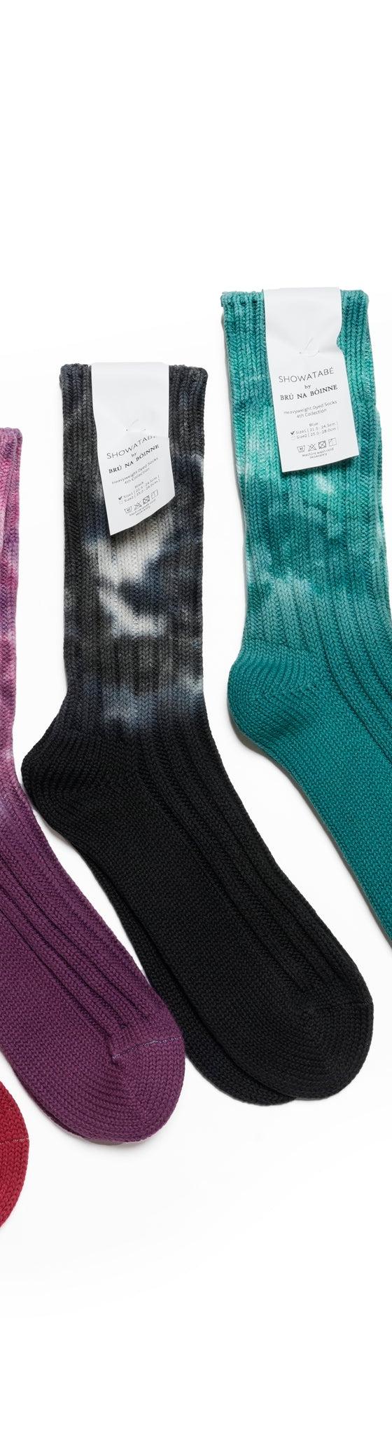 Five pairs of decka Quality Socks in tie-dyed red, purple, black, teal and yellow ribbed cotton on a white background