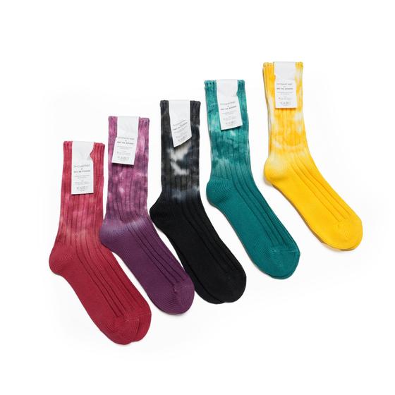 Five pairs of decka Quality Socks in tie-dyed red, purple, black, teal and yellow ribbed cotton on a white background