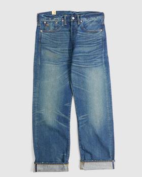 A pair of washed selvedge denim jeans with cuffed hems on a plain grey background