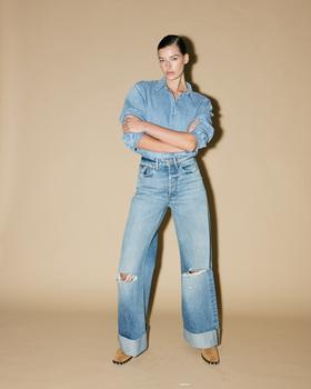 A woman wearing a light-wash DENHAM denim shirt and wide-leg cuffed jeans