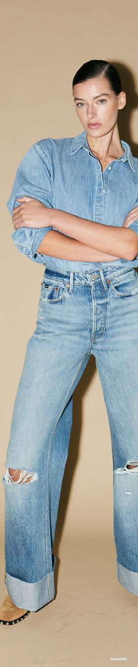 A woman wearing a light-wash DENHAM denim shirt and wide-leg cuffed jeans