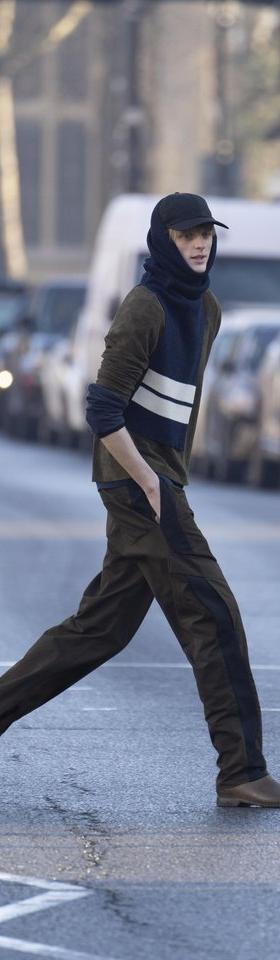 A man crossing a London street wearing a brown Derrick jacket and trousers with a navy striped knit scarf and cap