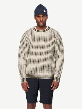 A man wearing a cream patterned Devold wool sweater and a navy beanie