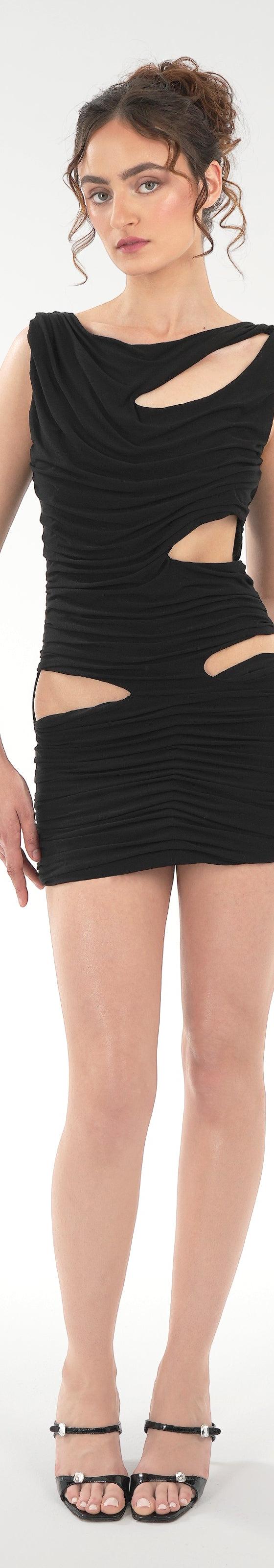 A woman wearing a black draped Di Petsa mini dress with cut-outs