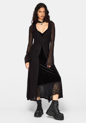 A woman wearing a black velvet lace-trim slip dress with a sheer knit longline cardigan and chunky platform boots