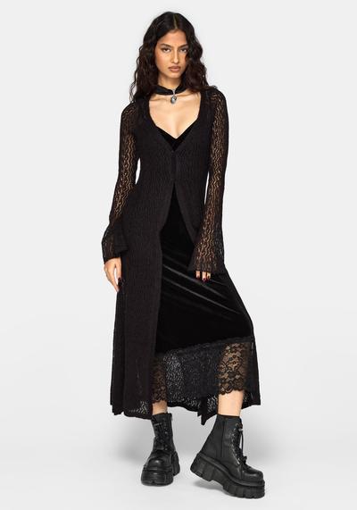 A woman wearing a black velvet lace-trim slip dress with a sheer knit longline cardigan and chunky platform boots