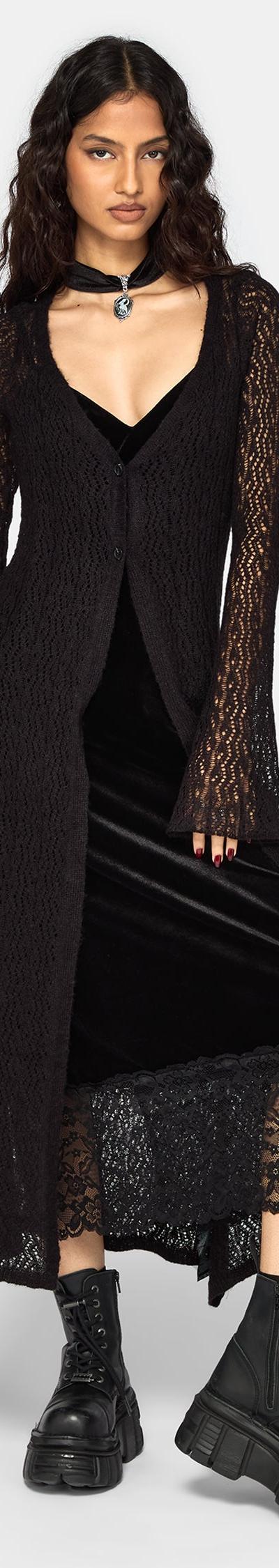 A woman wearing a black velvet lace-trim slip dress with a sheer knit longline cardigan and chunky platform boots