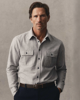 A man wearing a grey donegal flannel overshirt with navy trousers