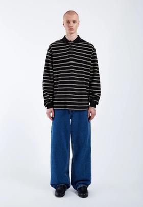 A man wearing a black and white striped Dr. Denim long-sleeve top with wide blue jeans