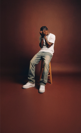 A man wearing light-wash distressed Dripcity jeans with a white T-shirt and white sneakers