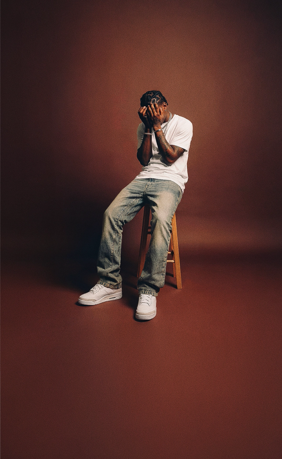 A man wearing light-wash distressed Dripcity jeans with a white T-shirt and white sneakers
