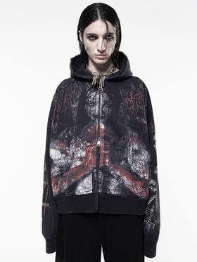 A model wearing an oversized black zip-up hoodie with a distressed horror print by Drop Dead Clothing
