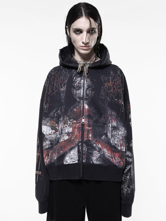 A model wearing an oversized black zip-up hoodie with a distressed horror print by Drop Dead Clothing