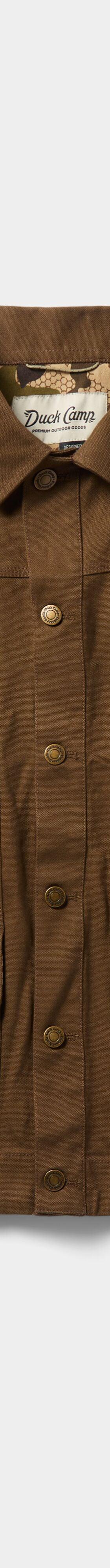 A brown waxed canvas Duck Camp chore jacket on a plain background