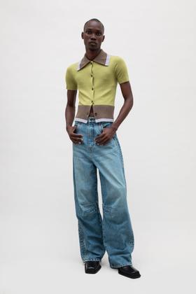 A man wearing a chartreuse ribbed EGONlab polo cardigan with wide-leg blue jeans