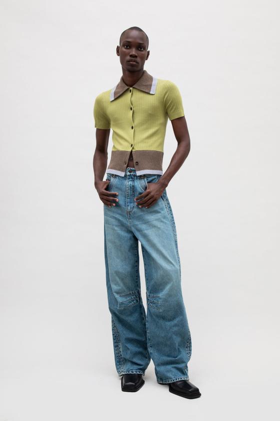 A man wearing a chartreuse ribbed EGONlab polo cardigan with wide-leg blue jeans