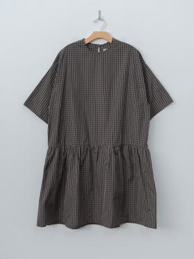 A brown checked ELEPH smock dress with gathered waist on a wooden hanger