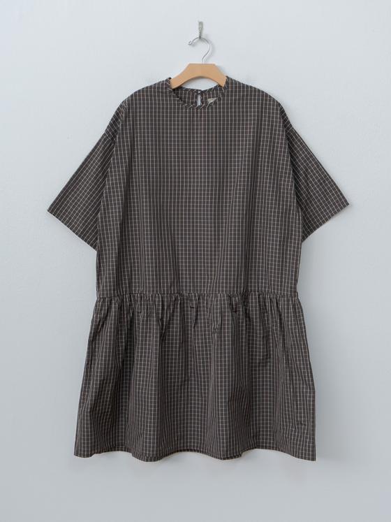 A brown checked ELEPH smock dress with gathered waist on a wooden hanger