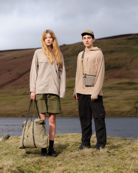 Two models in the hills, one carrying an olive Elliker tote bag and the other a beige crossbody pouch