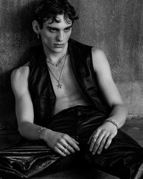 A man wearing an Emanuele Bicocchi layered silver necklace, bracelets and rings with a leather vest and trousers