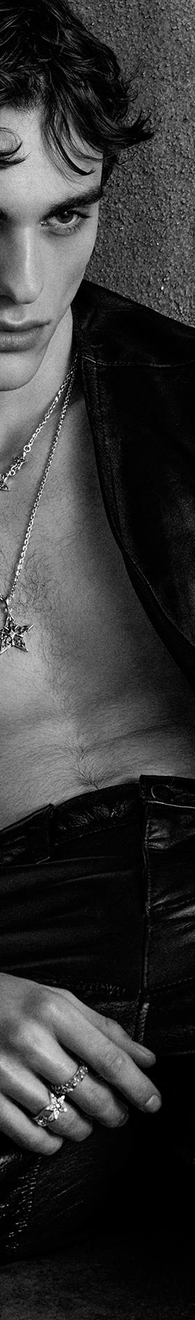 A man wearing an Emanuele Bicocchi layered silver necklace, bracelets and rings with a leather vest and trousers