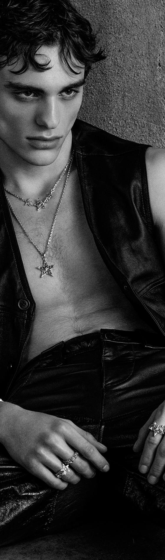 A man wearing an Emanuele Bicocchi layered silver necklace, bracelets and rings with a leather vest and trousers