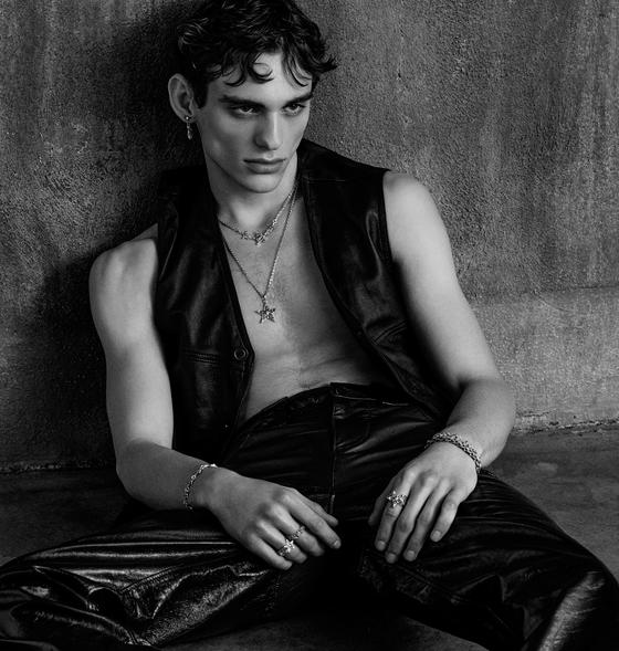 A man wearing an Emanuele Bicocchi layered silver necklace, bracelets and rings with a leather vest and trousers