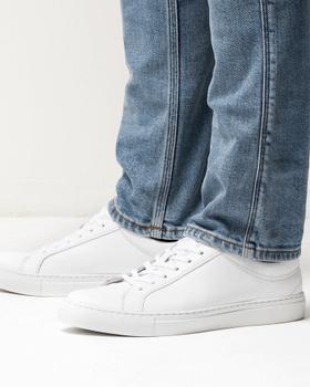A man wearing white Erik Schedin leather sneakers with blue jeans