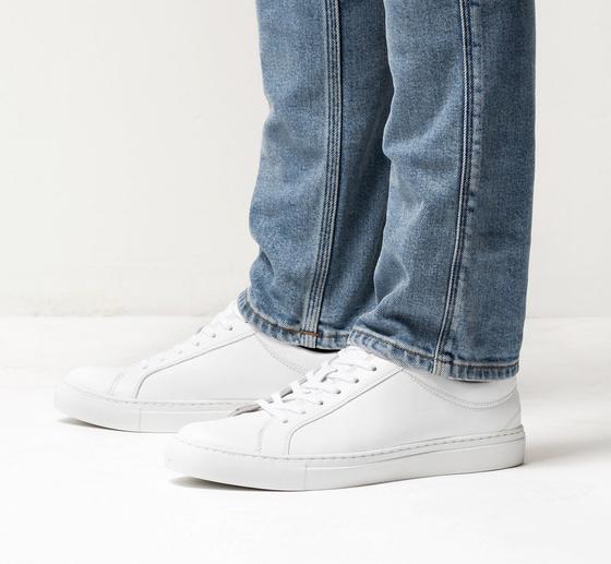 A man wearing white Erik Schedin leather sneakers with blue jeans