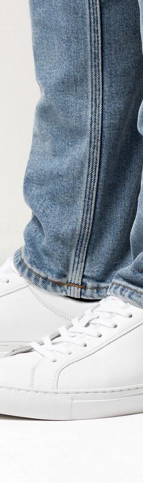 A man wearing white Erik Schedin leather sneakers with blue jeans