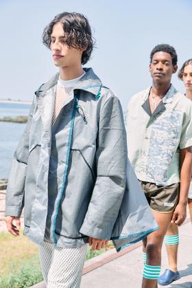 A man wearing a grey Estelita Mendonça deconstructed jacket with teal trim