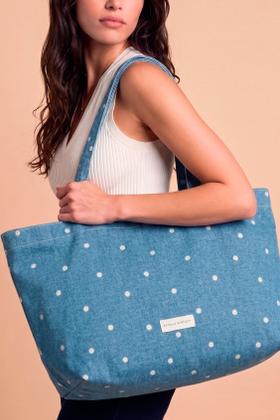 A woman carrying a blue denim Estella Bartlett tote bag with embroidered white daisies