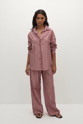 A woman wearing a pink striped Faithfull the Brand shirt and matching wide-leg trousers