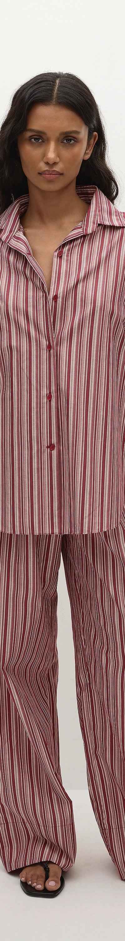 A woman wearing a pink striped Faithfull the Brand shirt and matching wide-leg trousers