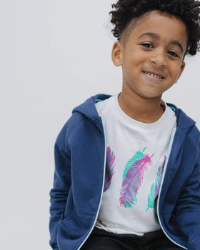 A young boy wearing a navy Firebird Kids zip-up hoodie over a feather-print tee