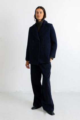 A woman wearing a navy textured wool Folk peacoat with matching wide-leg trousers