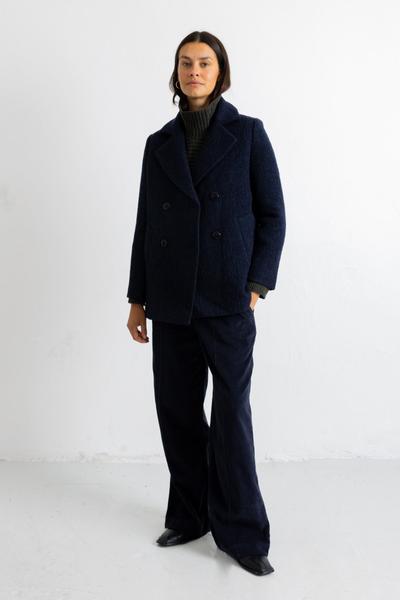 A woman wearing a navy textured wool Folk peacoat with matching wide-leg trousers