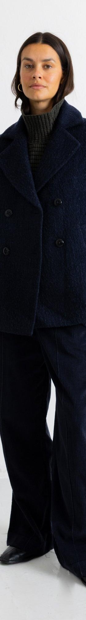 A woman wearing a navy textured wool Folk peacoat with matching wide-leg trousers