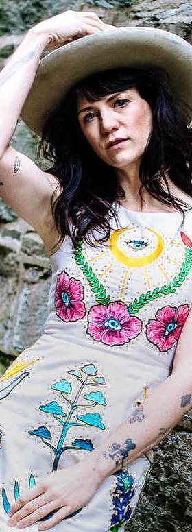 A woman in a wide-brim hat wearing a cream Fort Lonesome dress with colorful chainstitch floral embroidery