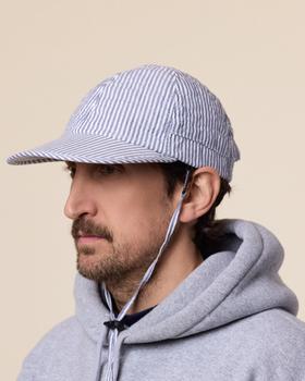 A man wearing a blue and white striped seersucker Found Feather cap with chin cord