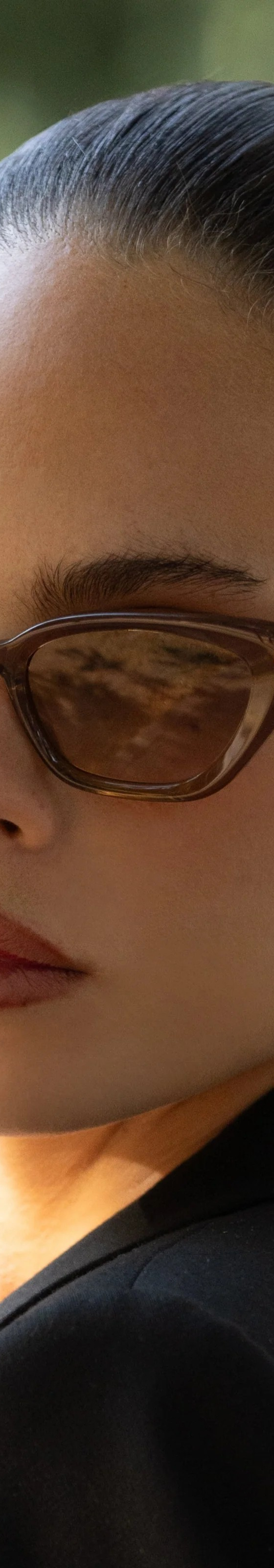 A woman wearing brown cat-eye FREYRS sunglasses with a black blazer