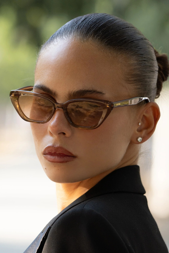 A woman wearing brown cat-eye FREYRS sunglasses with a black blazer