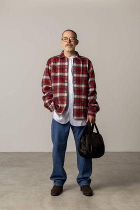 A man wearing a red checked FUJITO overshirt with blue jeans