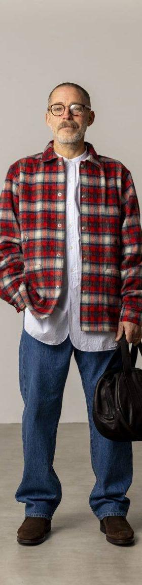 A man wearing a red checked FUJITO overshirt with blue jeans