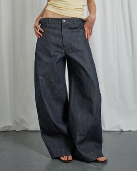 A woman wearing wide-leg indigo Gandaia jeans with a cream top