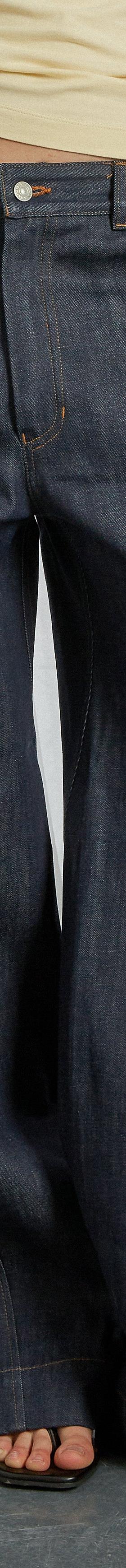 A woman wearing wide-leg indigo Gandaia jeans with a cream top