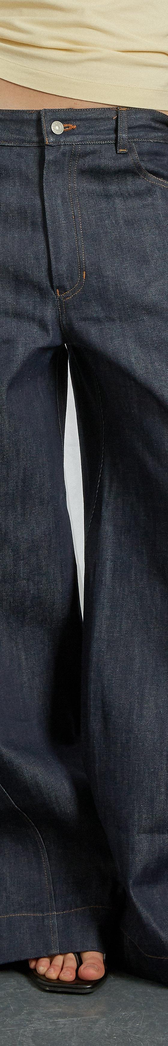 A woman wearing wide-leg indigo Gandaia jeans with a cream top